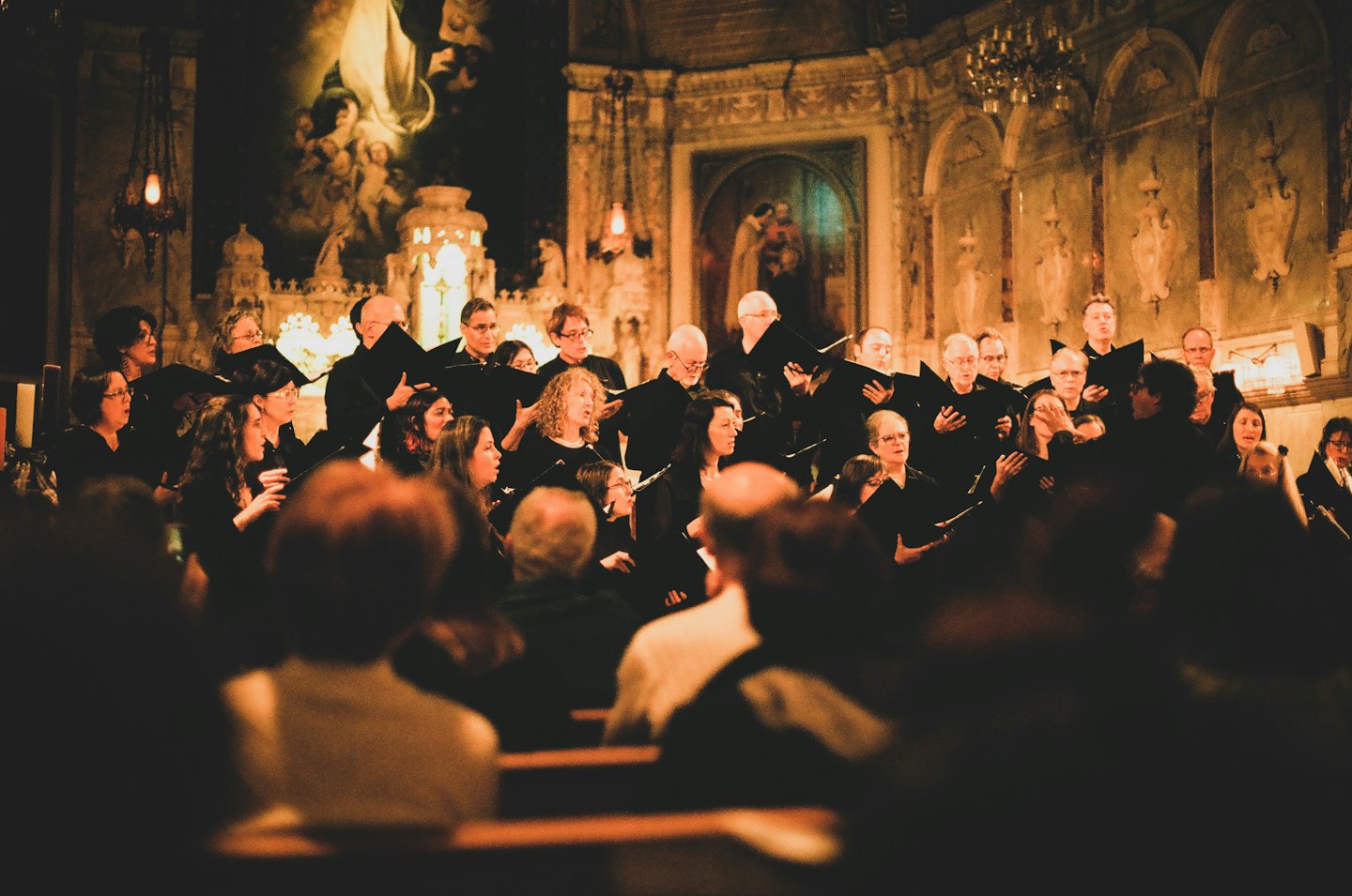 Een koor zingt uit bladmuziek in een grote kerkzaal.