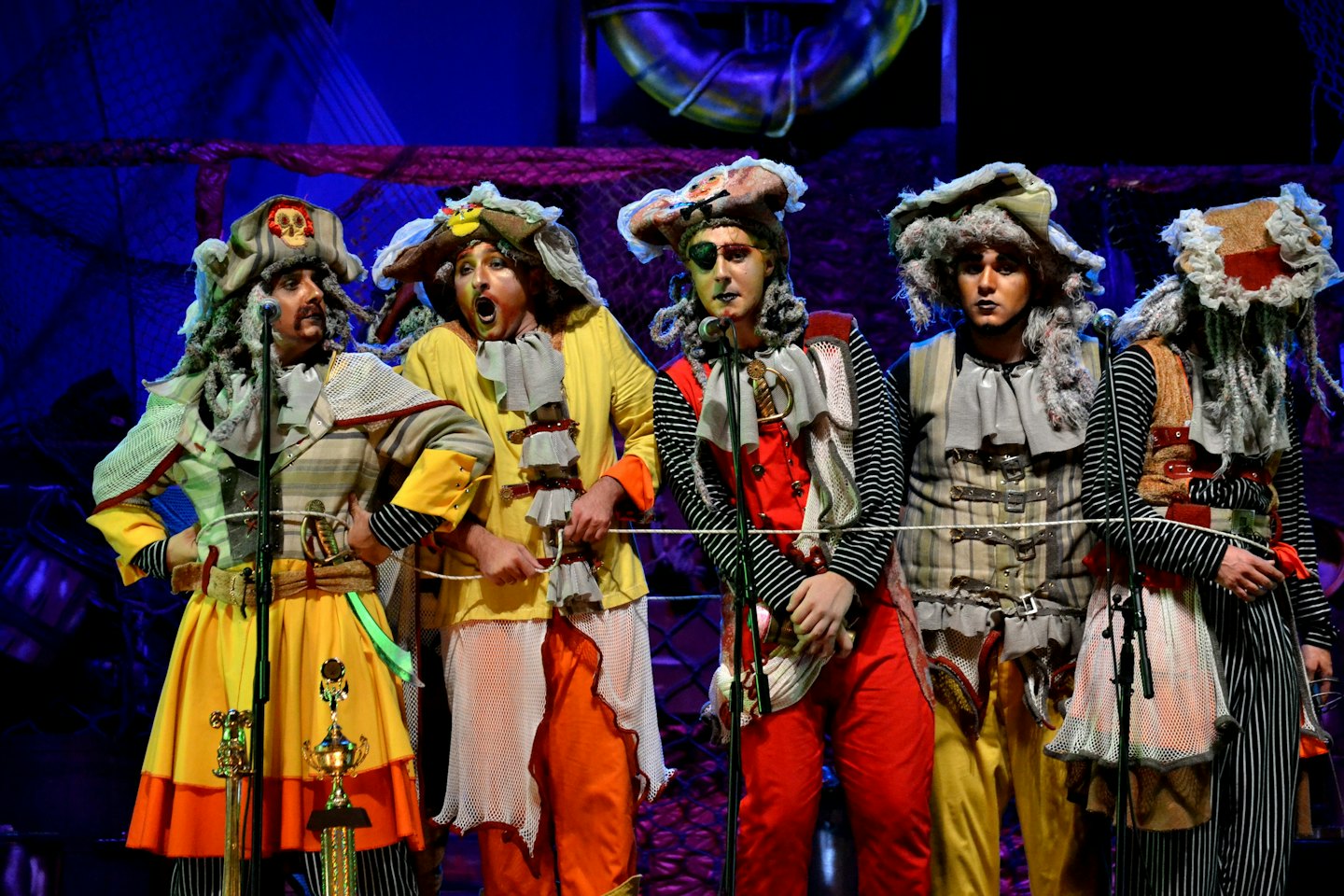 Artiesten in uitgebreide piratenkostuums staan met trofeeën op het podium.