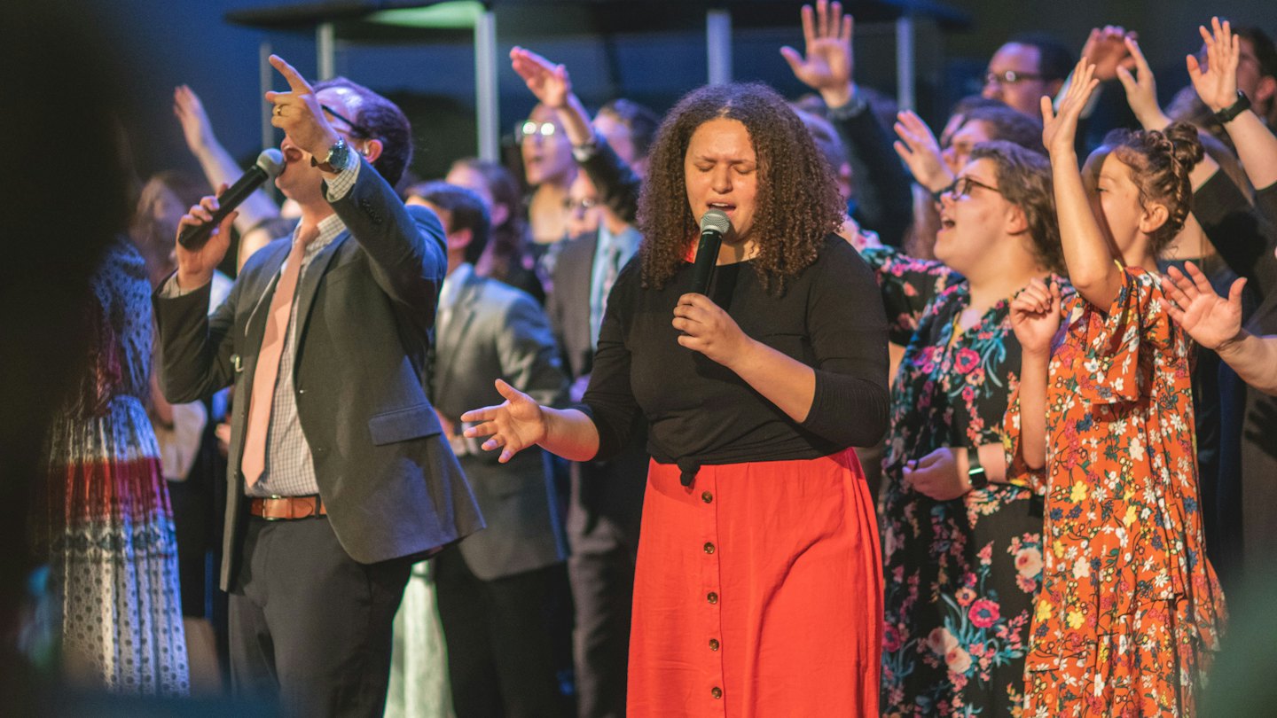 Diverse zangers zingen gepassioneerd met opgeheven handen.